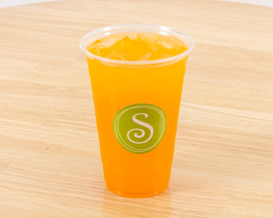 A clear plastic cup filled with orange juice and ice, featuring a green "S" logo.