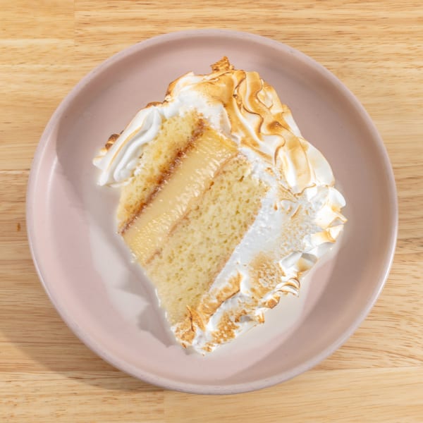 A slice of tres leches cake with toasted meringue topping on a pink plate.