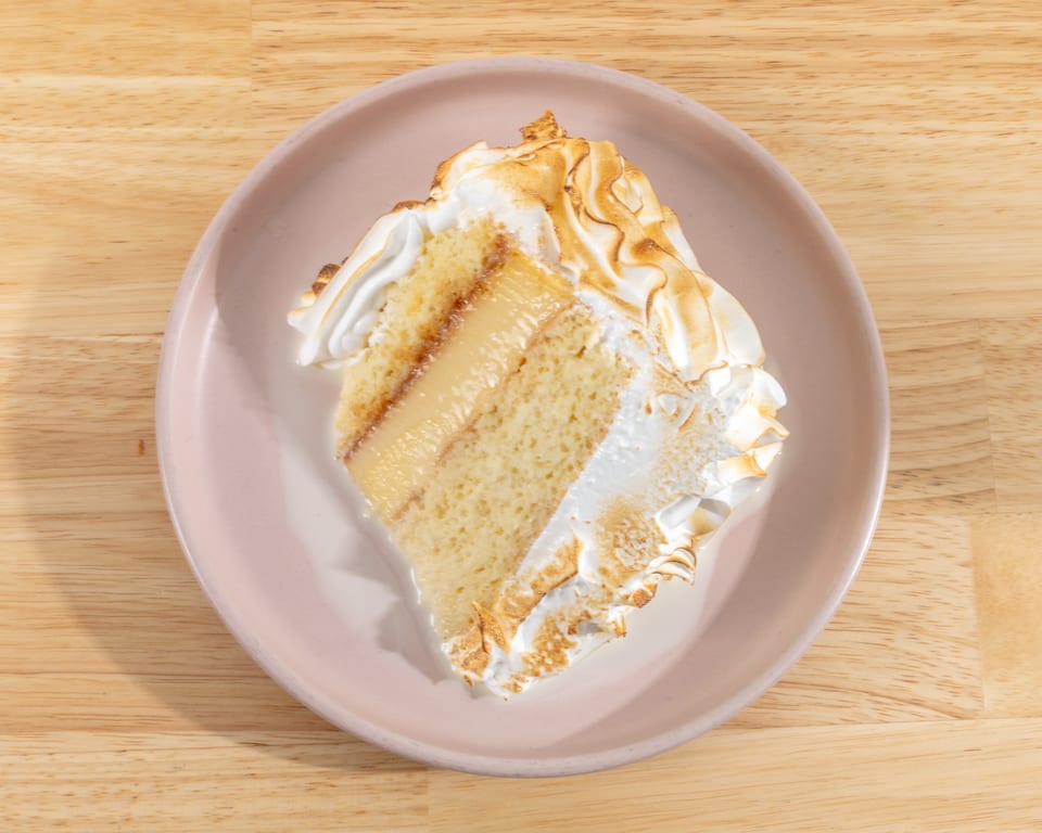 A slice of tres leches cake with toasted meringue topping on a pink plate.