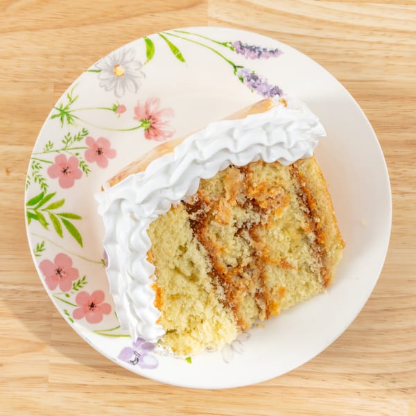 Slice of cake with white frosting and caramel swirls on a floral plate.